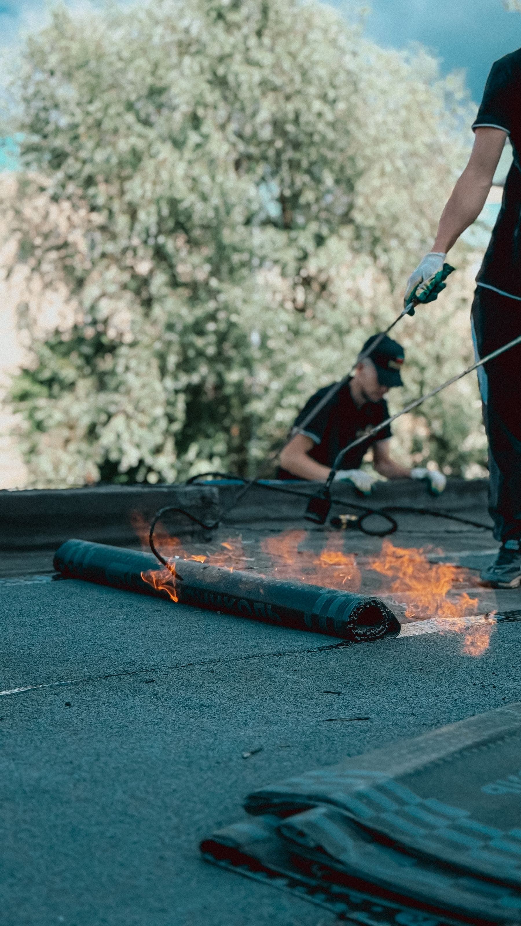 Roofer torching on a bitumen felt membrane on a flat roof