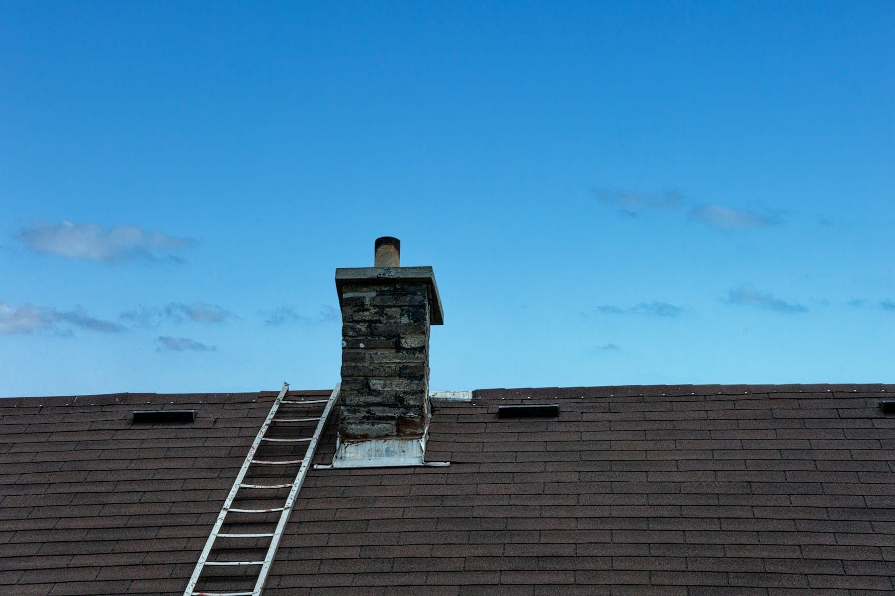 A roof ladder laid up a slate roof to a stone chimney during an inspection